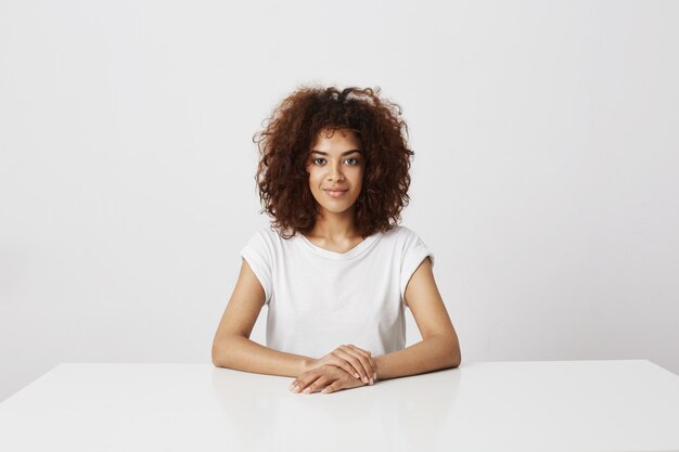 Portrait of attractive african girl smiling  over white wall