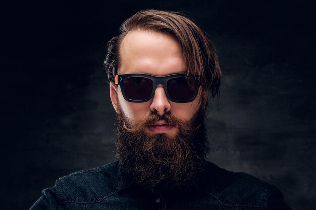 Portrait of attractive bearded man in sunglasses over dark background.