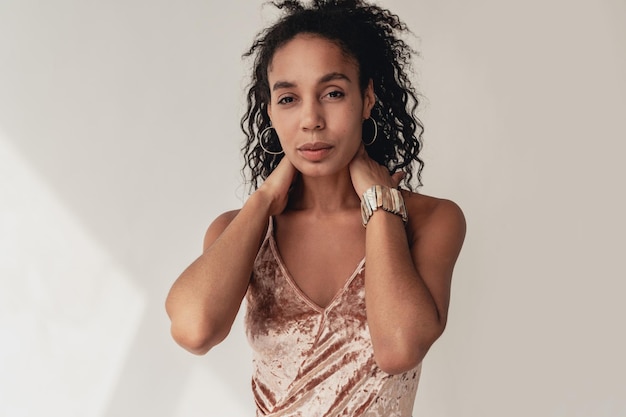 Portrait of attractive black african american woman in stylish outfit velvet top on white studio background summer fashion trend happy smiling curly hair accessories