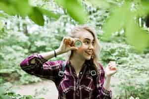 Free photo portrait of an attractive blond girl posing with a compass in a forest