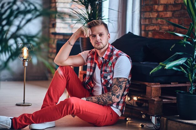 Portrait of attractive blond tattooed male in a room with loft interior.