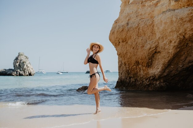 Portrait of attractive blonde girl with long hair posing on deserted beach.