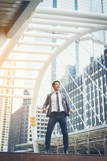 Portrait of Attractive businessman celebrates by jumping raises his fist overhead outdoor.