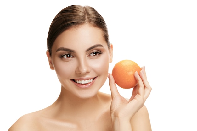 Portrait of attractive caucasian smiling holding an orange woman isolated on white