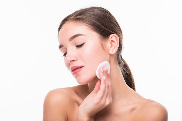 Portrait of attractive caucasian smiling woman cleaning her face isolated on white wall