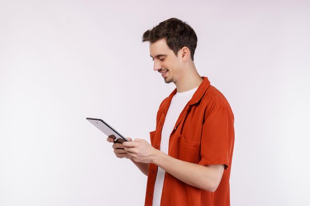 Portrait of attractive cheerful man using device app searching web isolated over white color background