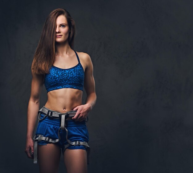 Portrait of attractive female free climber with protective gear over grey background.