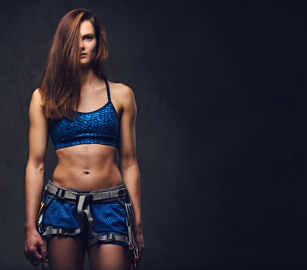 Portrait of attractive female free climber with protective gear over grey background.