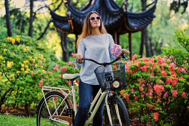 公園の伝統的な中国のパビリオンの近くにシティ自転車で魅力的な女性の肖像画。