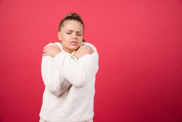 Portrait of an attractive girl hugging herself isolated over red background