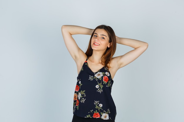 Free photo portrait of attractive lady holding hands behind head in blouse and looking cheerful front view