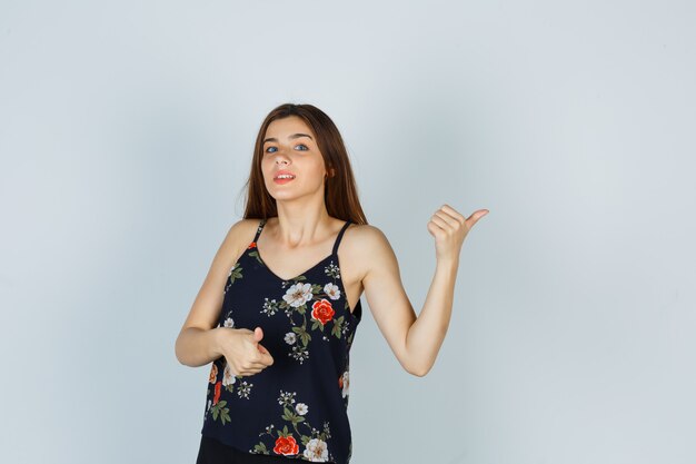 Free photo portrait of attractive lady showing thumbs up in blouse and looking confident front view