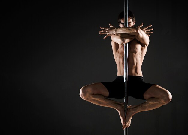 Portrait of attractive man performing a pole dance