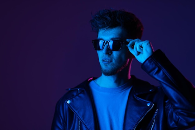 Portrait of attractive man wearing specs looking far away isolated over dark neon purple color background