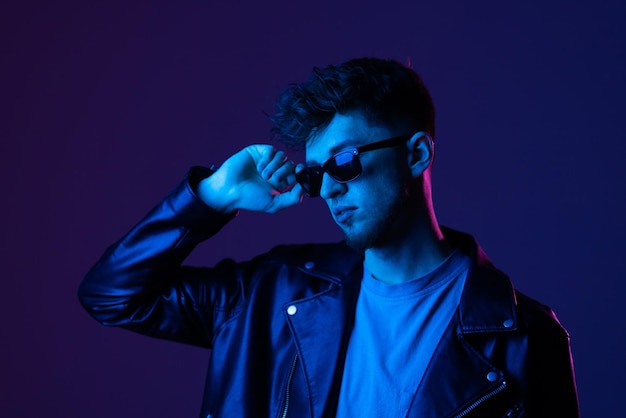 Portrait of attractive man wearing specs looking far away isolated over dark neon purple color background