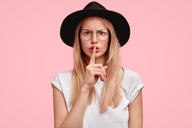 Portrait of attractive serious female looks with annoyed expression at camera