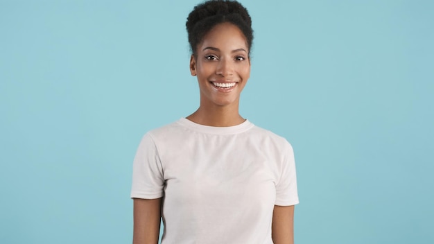 흰색 티셔츠를 입은 매력적인 웃고 있는 아프리카계 미국인 소녀의 초상화는 화려한 배경에서 카메라를 행복하게 보고 있습니다.