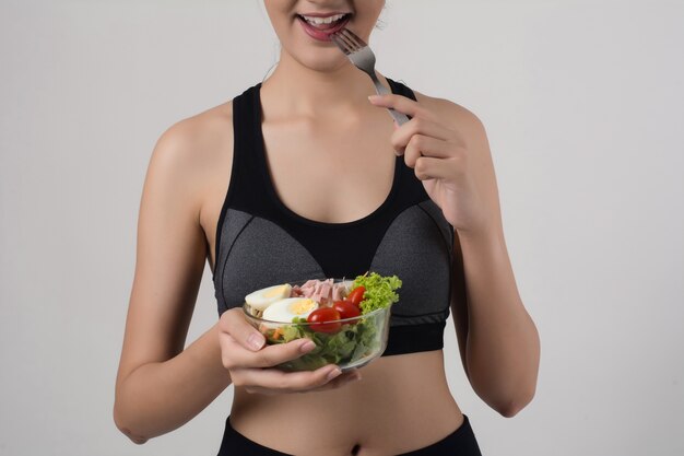 Portrait of attractive smiling woman eating salad isolated on white background.