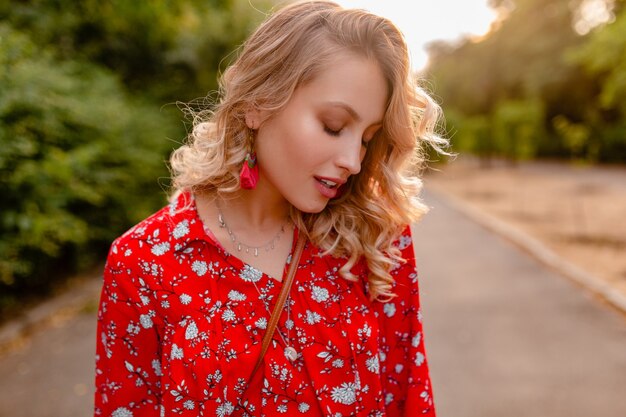 笑顔のイヤリングを身に着けている赤いブラウス夏のファッション衣装で魅力的なスタイリッシュな金髪の笑顔の女性の肖像
