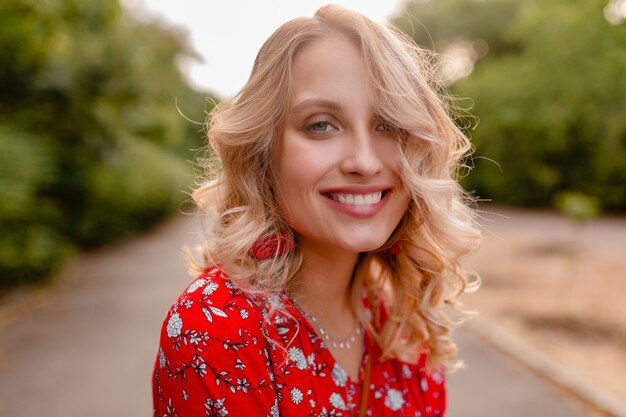 Portrait of attractive stylish blond smiling woman in red blouse summer fashion outfit  wearing earrings smiling