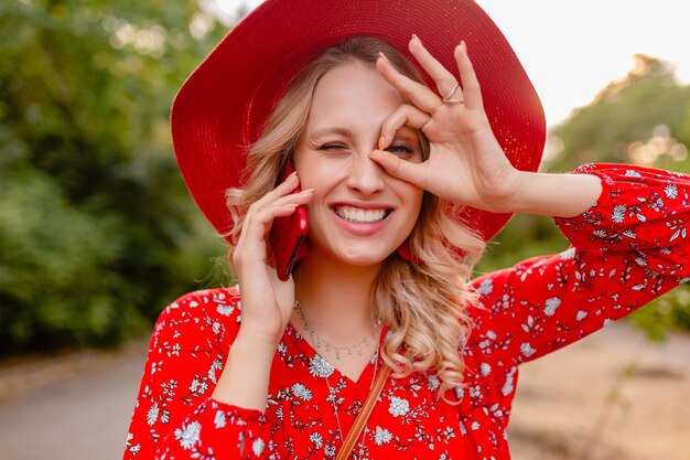 밀짚 빨간 모자와 블라우스 여름 패션 복장에 매력적인 세련된 금발 웃는 여자의 초상화 전화 긍정적 인 제스처 감정에 이야기