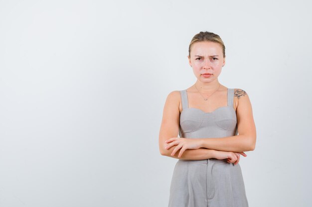 Portrait of attractive woman crossing hands in low cut gray suit with tattoo and looking very angry