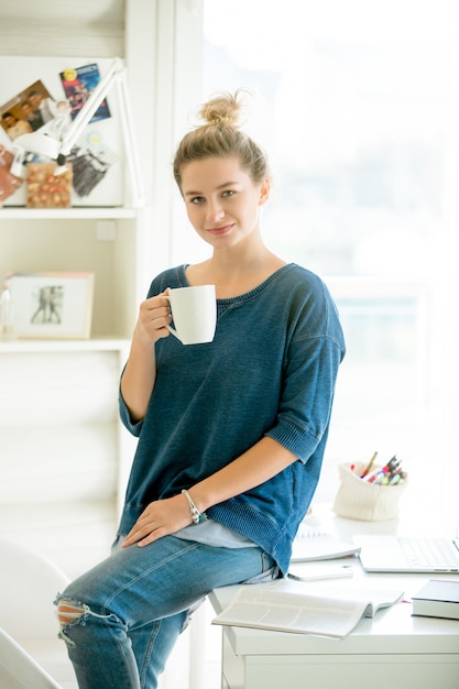 Portrait of an attractive woman half-sitting at the table