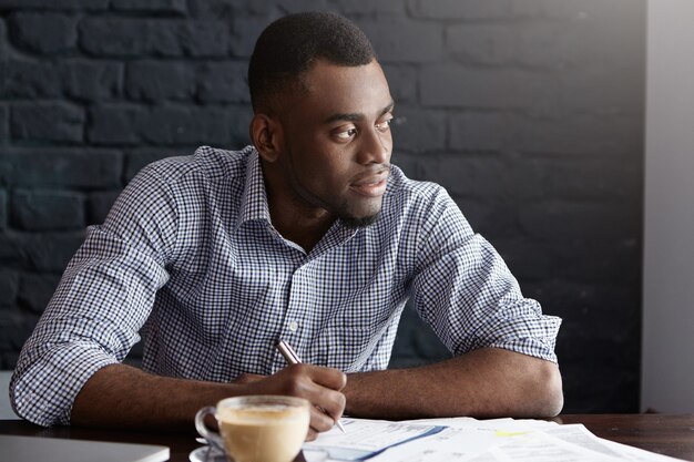 Portrait of attractive young African-American CEO in shirt going through some paperwork