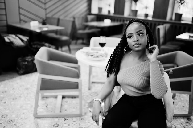 Portrait of attractive young african american woman wearing in green sweater and black jeans pose at restaurant