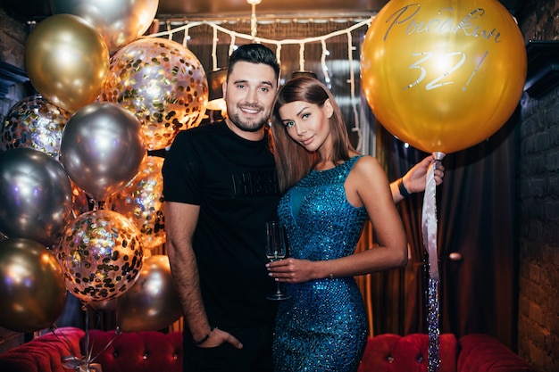 Portrait of attractive young couple in the club with air balloon