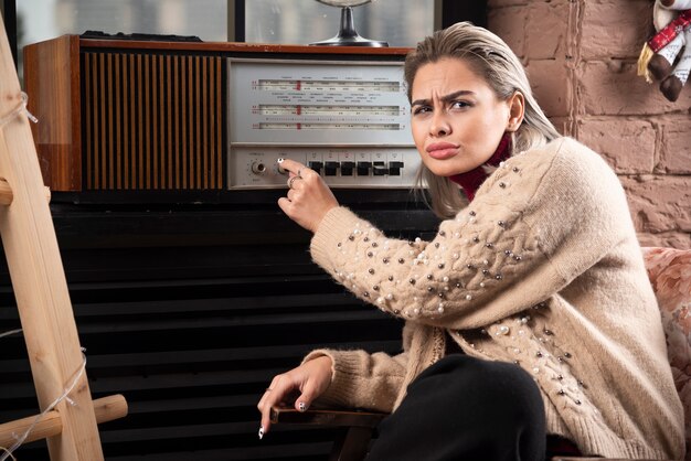 Portrait of an attractive young girl turning record player while sitting and looking away