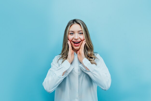 Portrait of an attractive young girl who is surprised, with a smile on blue