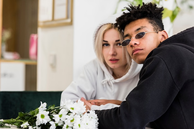 Foto gratuita ritratto di un attraente giovane coppia interrazziale con bouquet di fiori bianchi