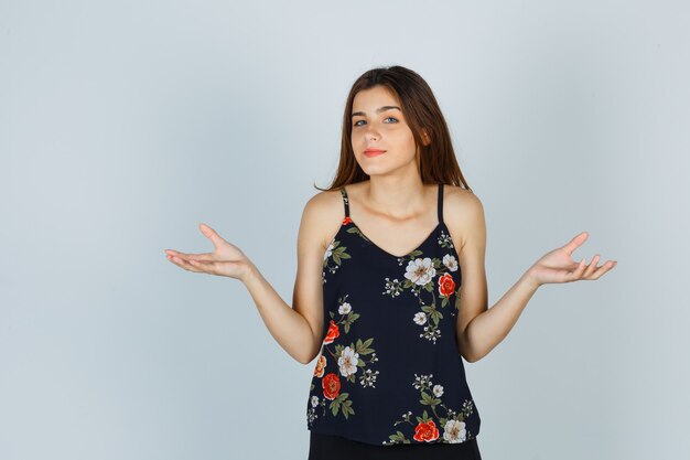 Portrait of attractive young lady showing helpless gesture in blouse and looking clueless front view