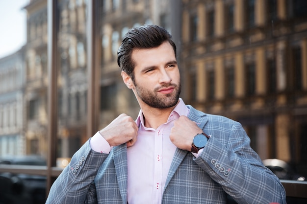 Portrait of an attractive young man straightening his jacket