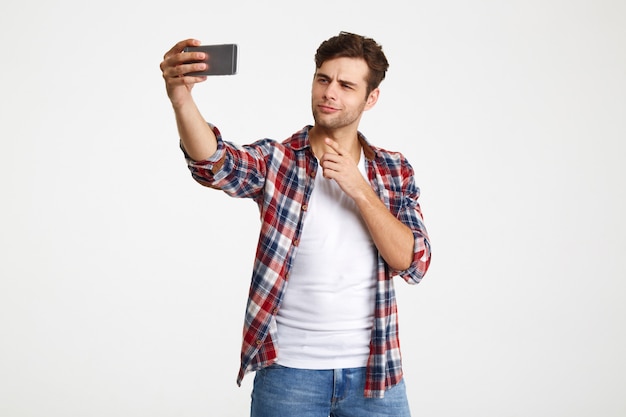 Foto gratuita ritratto di un giovane attraente che prende un selfie