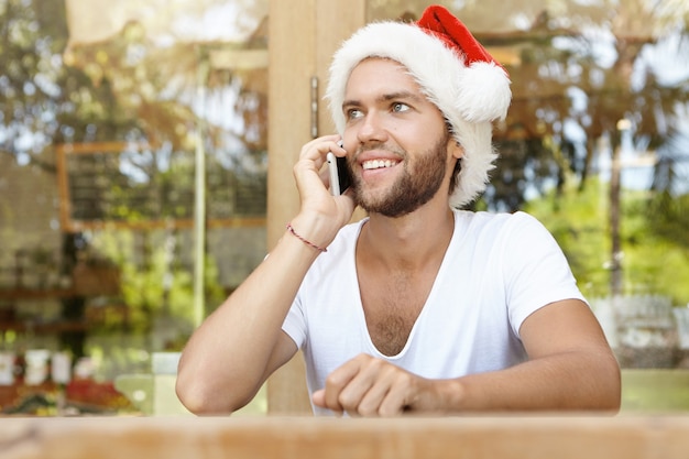 Portrait of attractive young man with happy joyful smile dressed in red hat