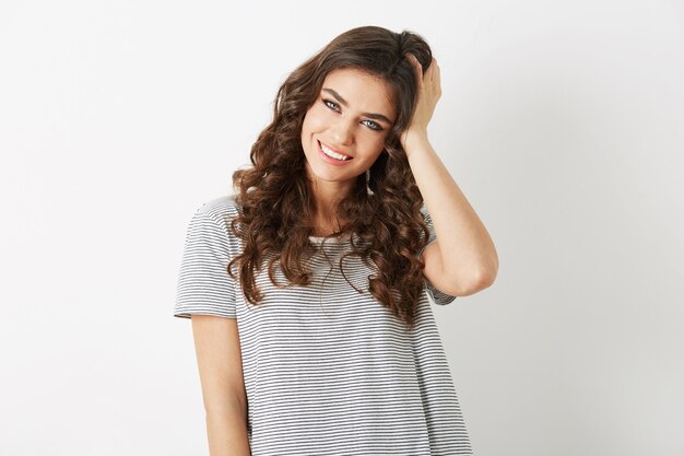 Portrait of attractive young woman holding her curly hair smiling isolated on white studio background, dressed in t-shirt, casaual style, looking in camera, natural look, beautiful hipster model