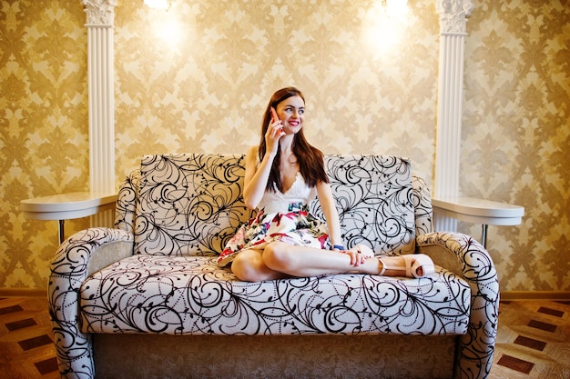 Attractive Young Woman Talking on the Phone While Sitting on the Sofa