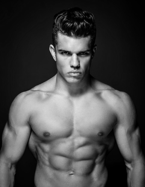 Portrait of awesome male model with naked muscular body. Isolated on dark grey background.