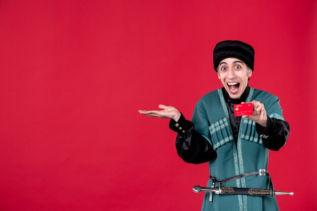 Портрет азербайджанского мужчины в традиционном костюме, держащего кредитную карту на красных деньгах, весенний этнический цвет новруз