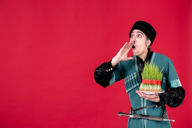 Portrait of azeri man in traditional costume holding green semeni on red dancer ethnic novruz spring