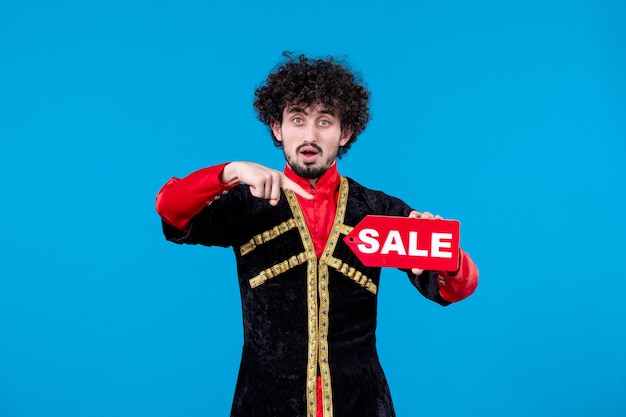 Portrait of azeri man in traditional costume holding sale nameplate on blue background ethnic novruz spring shopping photo