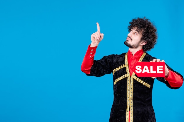 Portrait of azeri man in traditional costume holding sale nameplate blue background shopping concept spring novruz