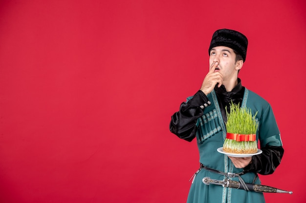 Portrait of azeri man in traditional costume holding semeni studio shot on red novruz concept performer