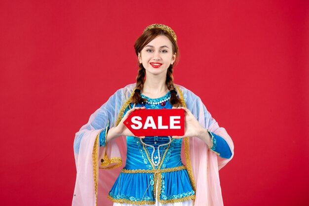 Portrait of azeri woman in traditional dress holding sale nameplate on red