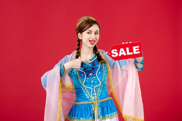 Portrait of azeri woman in traditional dress holding sale nameplate on red