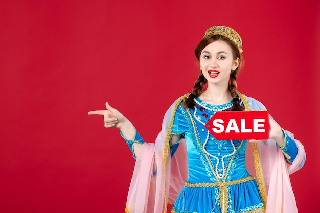 Portrait of azeri woman in traditional dress holding sale nameplate on red