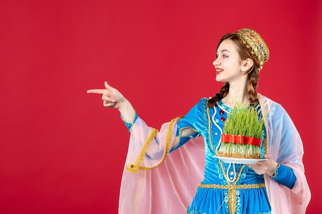 Free photo portrait of azeri woman in traditional dress holding semeni on red