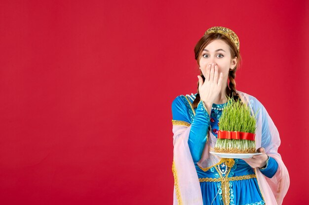 Portrait of azeri woman in traditional dress holding semeni on red